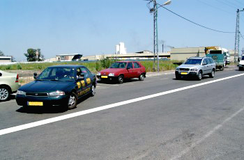 How should the driver of the silver vehicle respond, when the driver of the dark vehicle wants to park his vehicle in reverse between two vehicles next to the sidewalk?